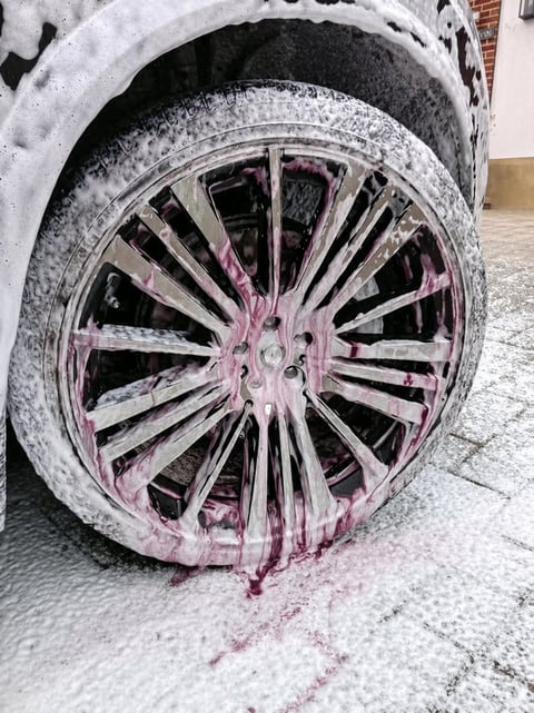 Car wheel with pink and purple splatter paint covering the chrome rim and snowy tire