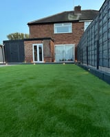 House with green lawn and dark metal fence